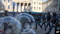 ARCHIVO - Policías pasan junto a un vendedor de globos mientras controlan una calle durante una protesta no autorizada ante el edificio de la Fiscalía General Rusa en Moscú, el sábado 27 de julio de 2019.