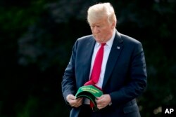 FILE - President Donald Trump holds hats reading "Make Our Farmers Great Again!" as he walks across the South Lawn before boarding Marine One at the White House in Washington, Aug. 30, 2018, before heading to a rally in Evansville, Indiana.