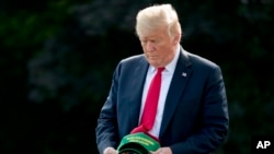 FILE - President Donald Trump holds a hat reading "Make Our Farmers Great Again!" as he walks across the South Lawn before boarding Marine One at the White House in Washington, Aug. 30, 2018, before heading to a rally in Evansville, Indiana.