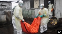 Health workers in protective gear carry the body of a woman suspected to have died from Ebola virus, from a house in New Kru Town at the outskirt of Monrovia, Liberia, Oct. 8, 2014. 