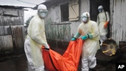 Health workers in protective gear carry the body of a woman suspected to have died from Ebola virus, from a house in New Kru Town at the outskirt of Monrovia, Liberia, Oct. 8, 2014. 