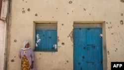 Une femme se tient devant une maison endommagée par les tirs lorsque les forces fédérales sont entrées dans la ville de Wukro, au nord de Mekele, dans le Tigré, le 1er mars 2021. 