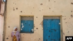 FILE - A woman leans on the wall of a damaged house which was shelled as federal-aligned forces entered the city, in Wukro, north of Mekele, in Tigray, March 1, 2021. 
