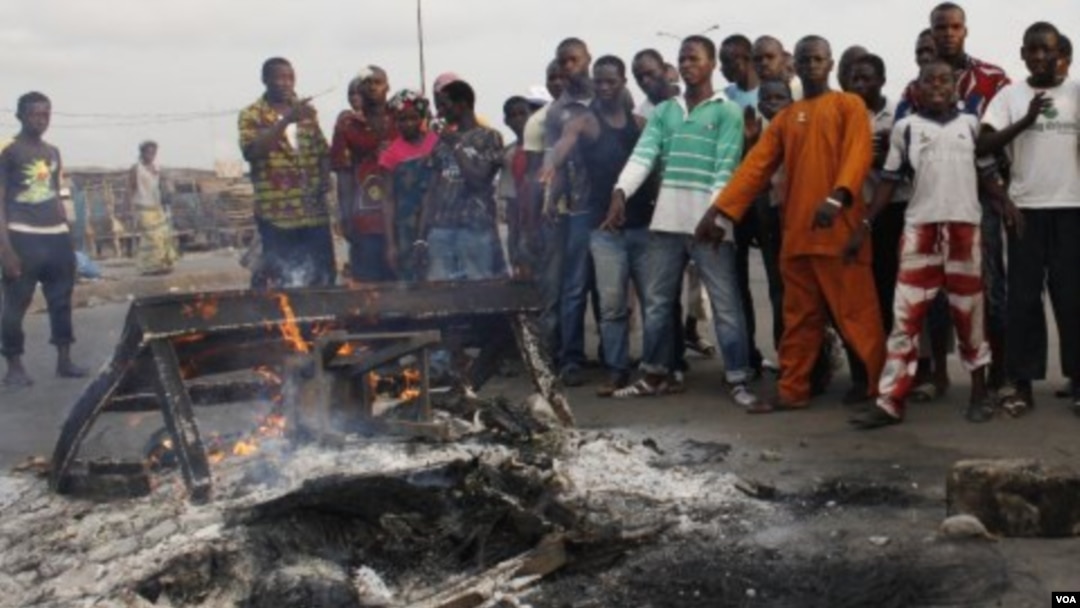 Pendukung presiden Alassane Ouattara menunjuk mayat yang terbakar yang diyakini sebagai pendukung Laurent Gbagbo, di Distrik Abobo, Abidjan (7/3).