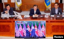 South Korean President Moon Jae-in looks at a TV broadcasting a news report on summit between the U.S. and North Korea during a cabinet meeting at the Presidential Blue House in Seoul, South Korea, June 12, 2018.