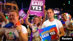 FILE - Participants hold banners of same-sex marriage during the 40th anniversary of the Sydney Gay and Lesbian Mardi Gras Parade in central Sydney, Australia, March 3, 2018.