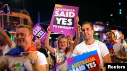 FILE - Participants hold banners regarding same-sex marriage during the 40th anniversary of the Sydney Gay and Lesbian Mardi Gras Parade in central Sydney, Australia, March 3, 2018.