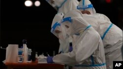 Medical staffers wearing protective suits work at a triage check point that was set to ease the pressure on hospital emergency wards, following the surge of COVID-19 case numbers, in Milan, Italy.