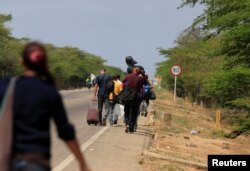 Venezuelans walk on a highway after crossing the border between Venezuela and Colombia, in Paraguachon, Colombia, February 16, 2018.