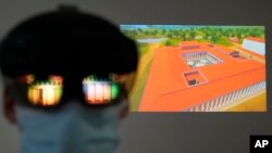The image of an ancient temple is reflected on a mixed-reality HoloLens headset worn by museum technician Kostas Baskakis as a projection of Ancient Olympia is seen in the background at the Olympic Museum in Athens, Greece, Tuesday, Nov. 9, 2021. (AP Phot