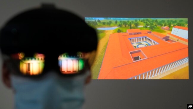 The image of an ancient temple is reflected on a mixed-reality HoloLens headset worn by museum technician Kostas Baskakis as a projection of Ancient Olympia is seen in the background at the Olympic Museum in Athens, Greece, Tuesday, Nov. 9, 2021. (AP Phot