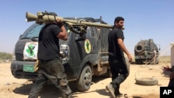 Iraqi counterterrorism forces fix their armored vehicles and load their weapons during a break in fighting outside Fallujah, Iraq, May 31, 2016. 