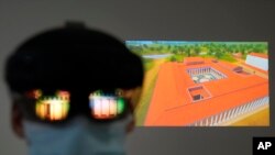 The image of an ancient temple is reflected on a mixed-reality HoloLens headset worn by museum technician Kostas Baskakis as a projection of Ancient Olympia is seen in the background at the Olympic Museum in Athens, Greece, Tuesday, Nov. 9, 2021. (AP Phot