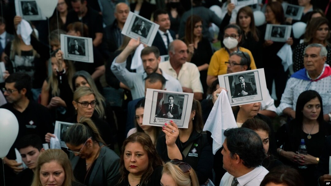 ARCHIVO - Personas, sosteniendo una imagen del difunto fiscal antidrogas Marcelo Pecci, asisten a una reunión para exigir justicia por su asesinato, en Asunción, Paraguay, el viernes 13 de mayo de 2022.
