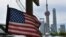 FILE - A U.S. flag flies on a U.S. Consulate car, with the backdrop of buildings in the Lujiazui financial district, in Shanghai, July 31, 2019. 