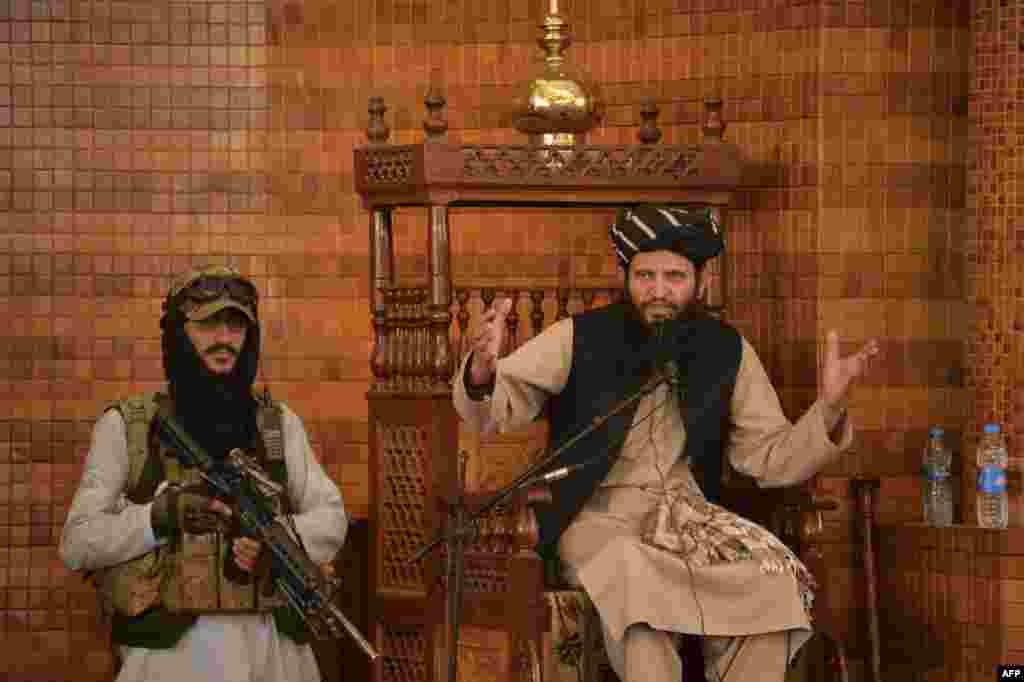 An Imam speaks next to an armed Taliban fighter during Friday prayers at the Abdul Rahman Mosque in Kabul, following the Taliban&#39;s takeover of Afghanistan.