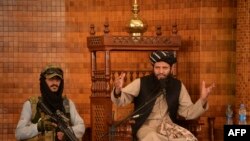 An Imam speaks next to an armed Taliban fighter during Friday prayers at the Abdul Rahman Mosque in Kabul, following the Taliban's stunning takeover of Afghanistan.