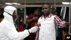 Nhân viên y tế đo thân nhiệt hành khách tại phi trường ở Lagos, Nigeria.