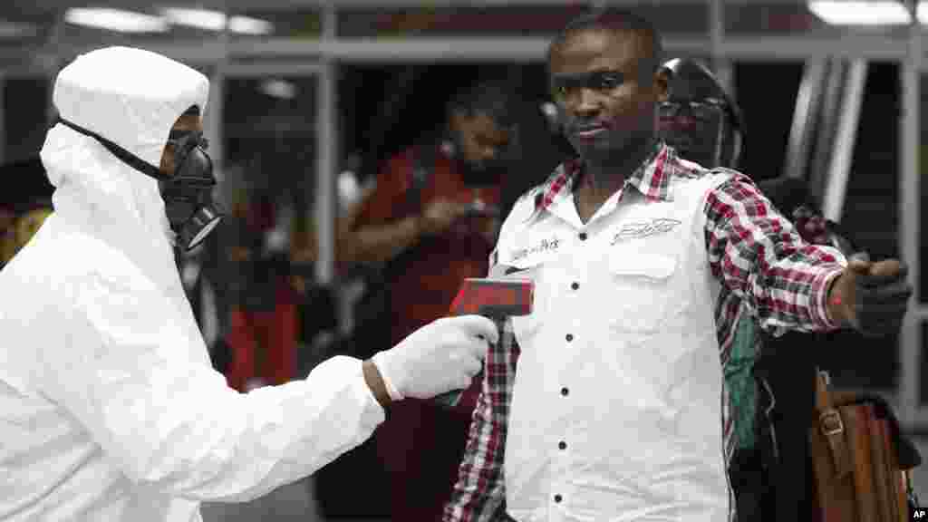 Afisa wa afya bandarini anatumia thermometerkumpima mfanyakazi katika uwanja wa ndege wa Murtala Mohammed Lagos, Nigeria.