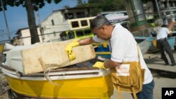 FILE - A health agent scoops water from a boat docked at the Jurujuba beach during an operation to eradicate the Aedes aegypti mosquito, in Niteroi, Brazil, March 8, 2016. Scientists in Brazil found a brain disorder linked to the Zika virus.