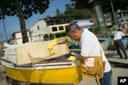 A health agent scoops water from a boat docked at Jurujuba Beach during an operation to eradicate the Aedes aegypti mosquito, in Niteroi, Brazil, March 8, 2016.