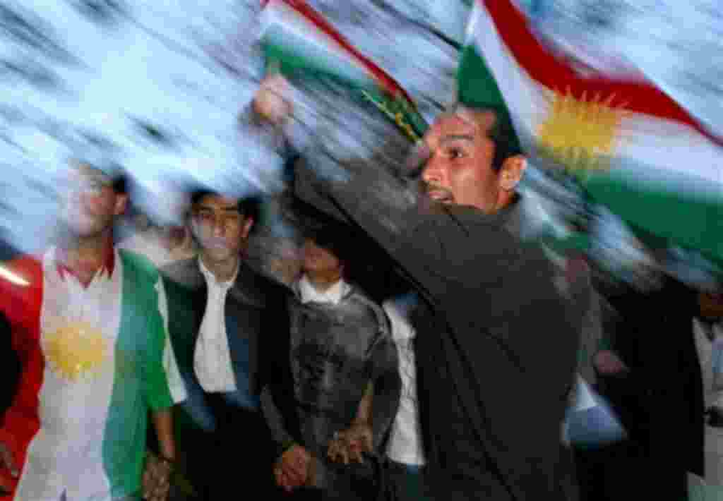 Kurdish men, one carrying the flag of Iraqi Kurdistan, celebrate the election of the new Iraqi President Jalal Talabani in Sulaimaniyah, Iraq, Wednesday, April 6, 2005. The Iraqi parliament chose Kurdish leader Talabani, reaching out to the nation's long-