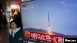 Hành khách đi qua màn hình tường thuật tin tức về vụ phóng hỏa tiễn của Bắc Triều Tiên tại nhà ga ở Seoul, Hàn Quốc, ngày 7/2/2016.