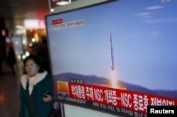 A passenger walks past a TV screen broadcasting a news report on North Korea's long range rocket launch at a railway station in Seoul, South Korea, Feb. 7, 2016.