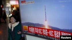 A passenger walks past a TV screen broadcasting a news report on North Korea's long range rocket launch at a railway station in Seoul, South Korea, Feb. 7, 2016.