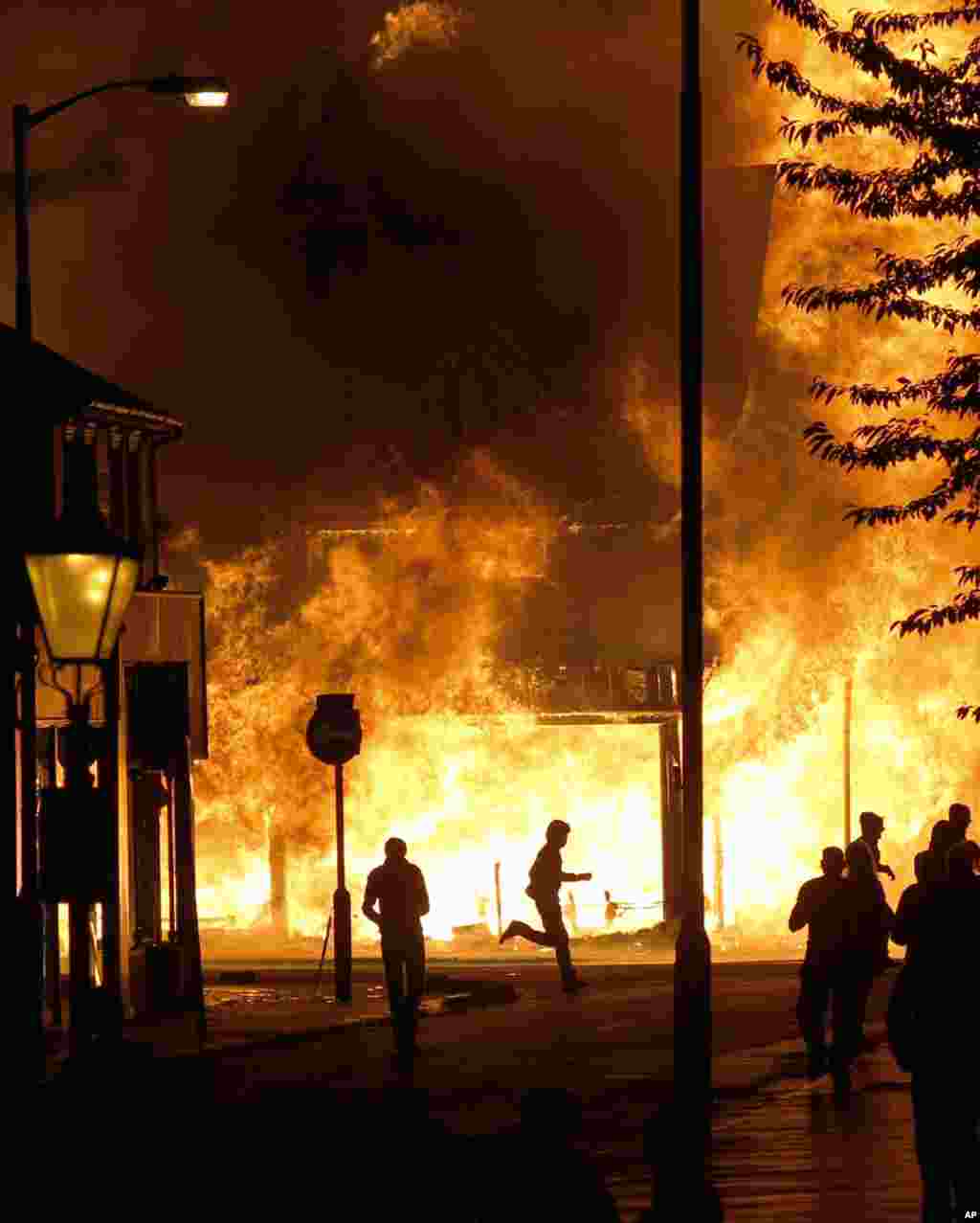 ALTERNATIVE CROP - A shop is set on fire as rioters gather in Croydon, south London, Monday, Aug. 8, 2011. Violence and looting spread across some of London's most impoverished neighborhoods on Monday, with youths setting fire to shops and vehicles, duri