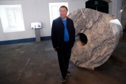 Dissident Chinese artist Ai Weiwei poses by one of his latest works, a giant toilet paper roll in marble, during a press preview of his new exhibition 'Rapture' in Lisbon, June 3, 2021.