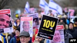 FILE - Demonstrators carry placards with the portraits of Israeli hostages and a placard reading "100 days in hell" during a march to mark the 100th day of the Israeli hostages' captivity during the ongoing Israeli-Palestinian conflict, on January 14, 2024 in Berlin, Germany.