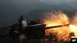 Syrian army personnel backed by Russian airstrikes fire cannon in Latakia province, near the border with Turkey, Oct. 10, 2015.