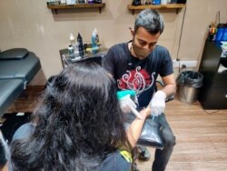 Max etches a memorial tattoo for the Gupta sisters who lost their father during the COVID pandemic's second wave. (Anjana Pasricha/VOA)