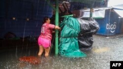 Una mujer asegura sus pertenencias en el mercado de San Isidro de La Ceiba, en Honduras, tras la llegada de la tormenta tropical Sara, el 15 de noviembre de 2024. (AFP/Esau Ocampo)