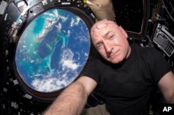 FILE - In this July 12, 2015 photo, Astronaut Scott Kelly takes a photo of himself inside the Cupola, a special module of the International Space Station that provides 360-degree viewing of the Earth and the station.