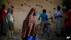 People walk through the heavily shelled police station in Gao, northern Mali, Feb. 11, 2013.