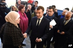 French President Emmanuel Macron shakes hands with a resident next to French Minister of Public Action and Accounts Gerald Darmanin, second right, during a visit to Tourcoing, Nov. 14, 2017.