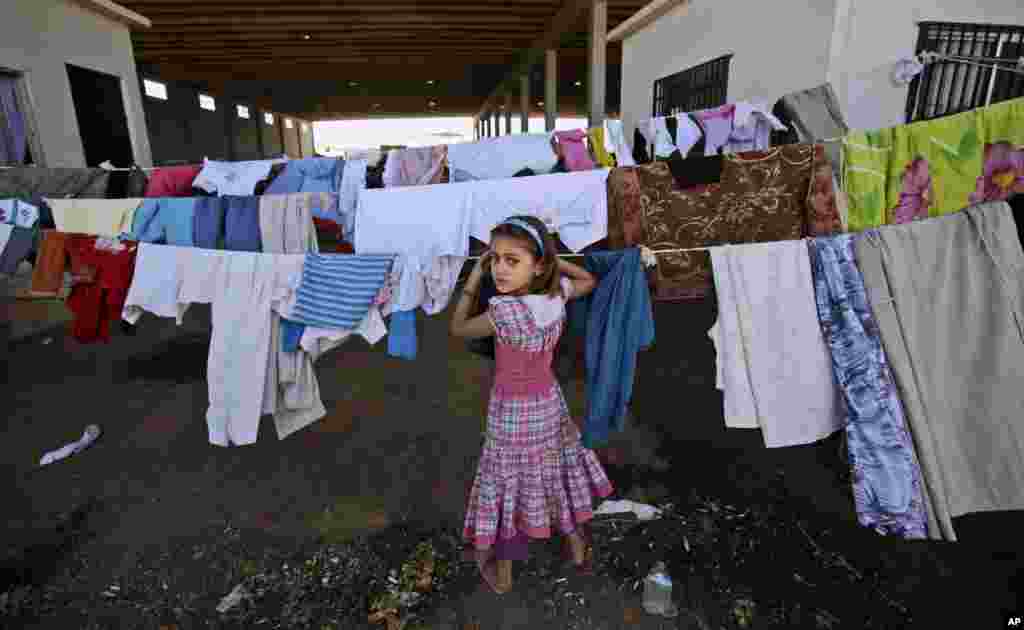 Seorang anak perempuan Suriah memeriksa jemurannya di tempat penampungan Bab Al-Salameh dekat kota perbatasan Azaz (26/8).