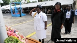 FILE - Liberian Minister of Justice Christine Tah (center right) observes a moment of silence with a senior female police officer at a 2011 ceremony for fallen peacekeepers.