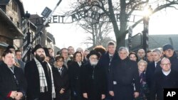 Rabbi Menachem Margolin, second left, the head of the European Jewish Association officials and lawmakers of the Parliament of Europe and Jewish leaders stand at the gate leading to the former Nazi German death camp of Auschwitz in Poland, Jan. 21, 2020.