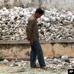 ຊາຍຄົນນື່ງຍ່າງຜ່ານ ກອງກະໂຫລກຫົວແລະກະດູກ ຂອງພວກທີ່ໄດ້ຮັບເຄາະຈາກການປົກຄອງອັນໂຫດຮ້າຍປ່າເຖື່ອນ ຂອງພວກຂະເໝນແດງ ໃນທ້າຍຊຸມປີ 1970 ທີ່ຍັງເກັບໄວ້ເປັນອະນຸສອນ ຢູ່ໂຮງຮຽນແຫ່ງນຶ່ງ ໃນເຂດຊານນະຄອນຫລວງພະນົມເປັນ.