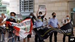 Pro-democracy activists including Leung Kwok-hung, second left, hold banners outside a district court in Hong Kong, Thursday, July 30, 2020. Activists including Lai who organized the June 4th Tiananmen massacre memorial this year, which was banned…