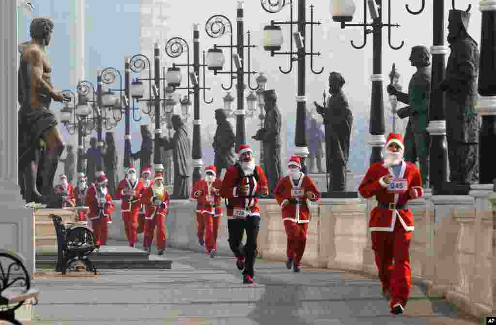 People costumed as Santa Claus run through a statue alley during a Santa Claus Race in Macedonia&#39;s capital Skopje.