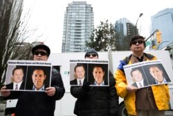 FILE - Protesters hold photos of Canadians Michael Spavor and Michael Kovrig, who are being detained by China, outside British Columbia Supreme Court, in Vancouver, March 6, 2019.