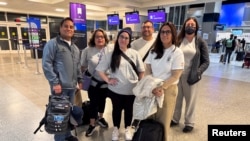 Ana María Haefmeyer, de 36 años, y Adamary 'Ada' García, de 40, posan para una foto junto con otras personas antes de abordar un vuelo a Chile, donde se reunirán con su familia biológica, en el Aeropuerto Intercontinental George Bush en Houston, Texas, el 21 de febrero.