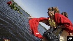 People throw flowers into the port of Kazan, Russia on the Volga River, in central Russia to mourn victims killed in the sinking of the boat the 'Bulgaria,' July 12, 2011