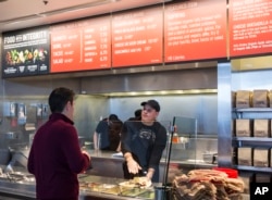 Chipotle Mexican Grill employee, right, prepares a burrito for a customer in Seattle.