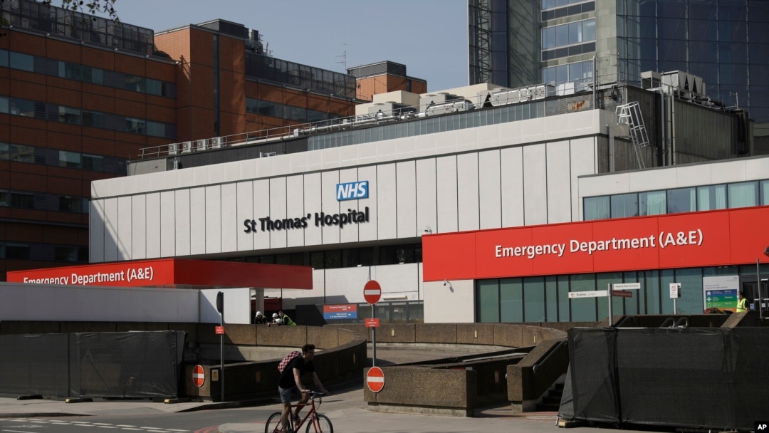 Workers who have been erecting and painting a fence over recent days, to block the view of the ambulance entrance, stand outside St Thomas' Hospital in London, where British Prime Minister Boris Johnson is being treated for coronavirus, April 10, 2020.