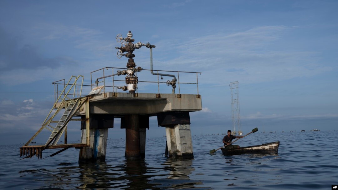 Un pescador navega frente a una perforadora petrolera fuera de operaciones en el lago Maracaibo en Venezuela, a principios del 12 de octubre de 2022. 